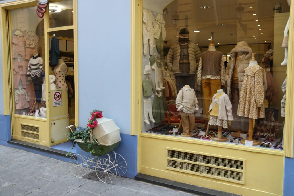 Clothing store window display with mannequins and clothes.